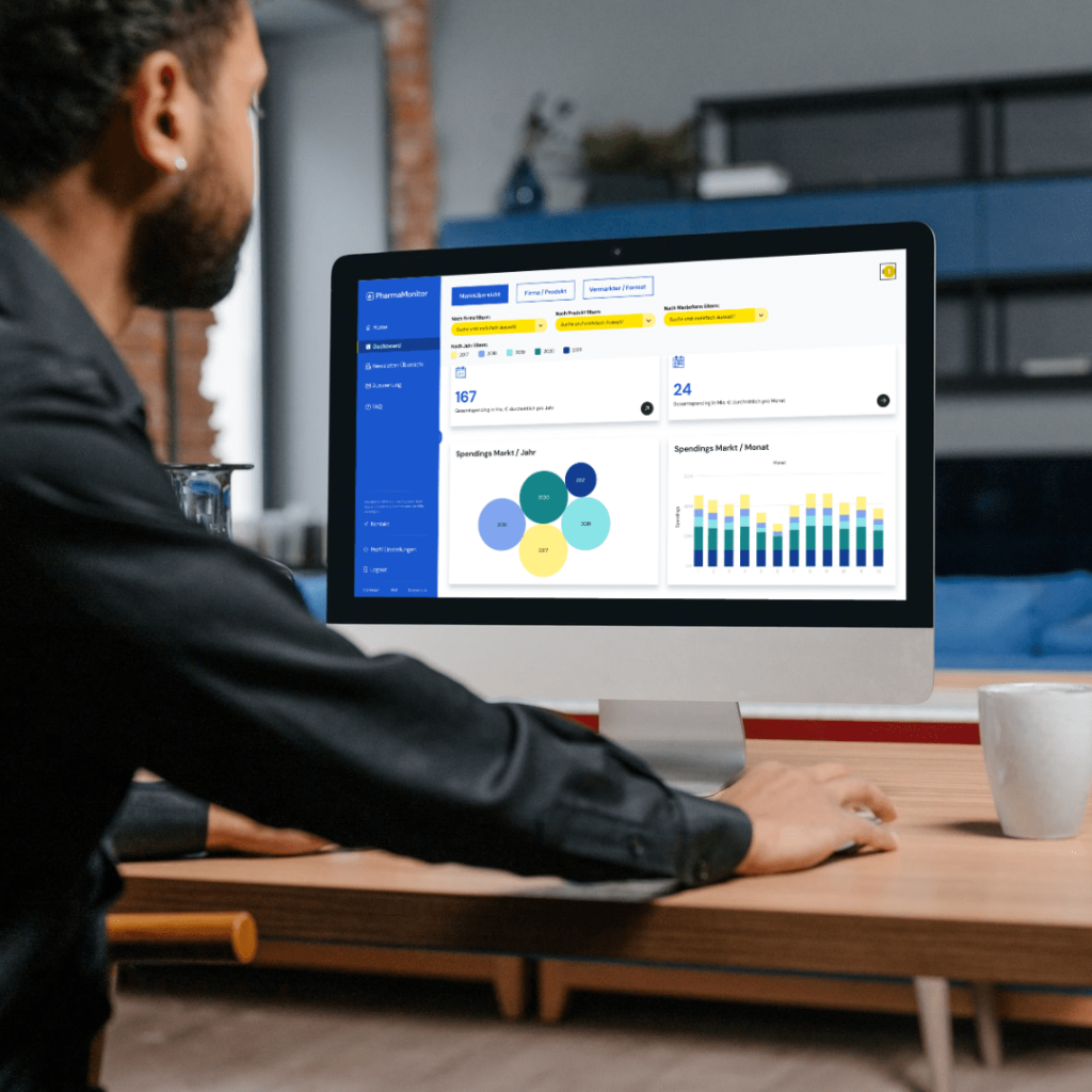 Mann sieht das Pharmamonitor Tableau Dashboard auf seinem Desktop-Arbeitsplatz an - Pharmamonitor